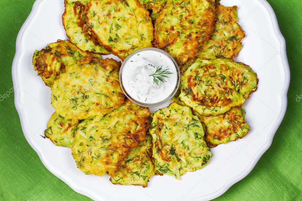 Zucchini Pancakes With  Sour Cream in White Plate.  
