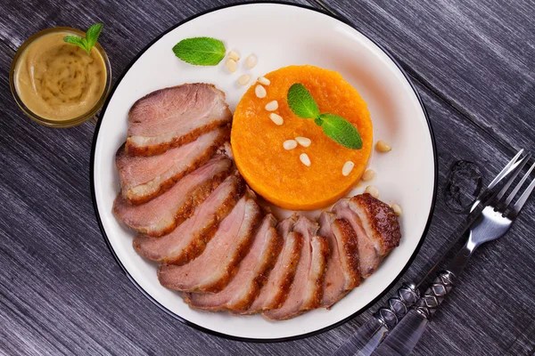 Roast duck breast and pumpkin mash, served with mint and pine nuts — Stock Image Roast duck breast and pumpkin mash, served with mint and pine nuts Royalty Free Stock Photos