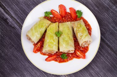 Lahana domates soslu et, pilav ve sebze ile alır. Etli lahana dolması yaprakları