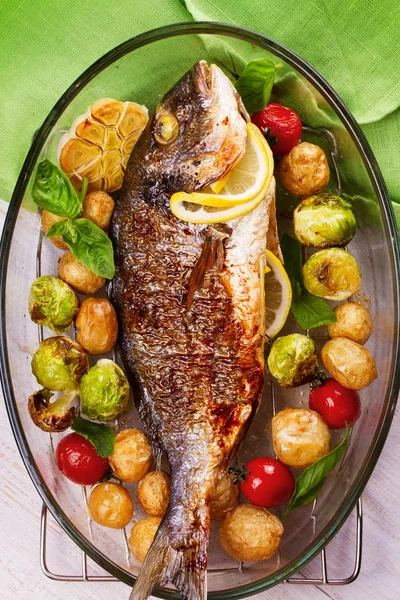 Ψάρι ψητό dorado με λαχανάκια Βρυξελλών, ντομάτες, σκόρδο, νέοι πατάτες και χόρτα — Φωτογραφία Αρχείου