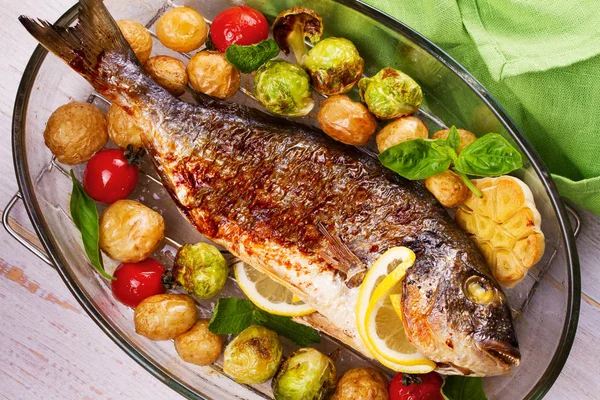 Pečené ryby dorado s růžičkovou kapustu, rajčata, česnek, mladých brambor a zelené — Stock fotografie