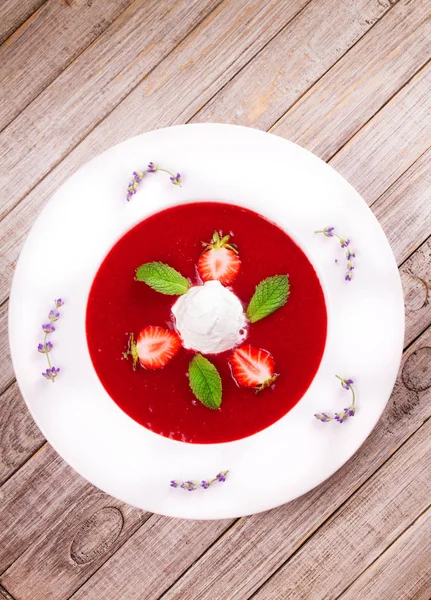 Strawberry soup with ice cream and mint. Pureed strawberries garnished with mint leaves topped with vanilla ice cream. Blended berries. Berry dessert