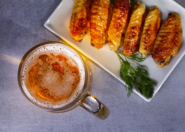 Un vaso de cerveza y alitas de pollo. Picaduras de cerveza — Foto de Stock