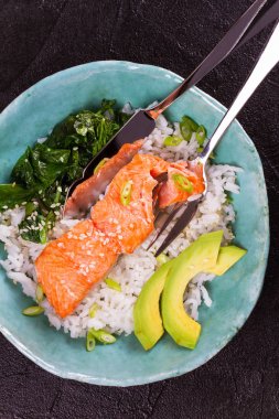 Ispanak ve avokado ile somon. Pirinç ve susam tohumu ile balık