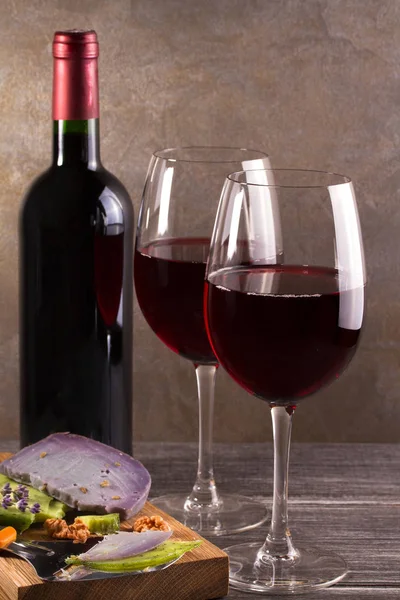 चष्मा आणि द्राक्ष, लावेंडर आणि पेस्टो चीजसह लाल वाइनची बाटली चॉपिंग बोर्डवर. वाईन आणि अन्न अजूनही जीवन — स्टॉक फोटो, इमेज