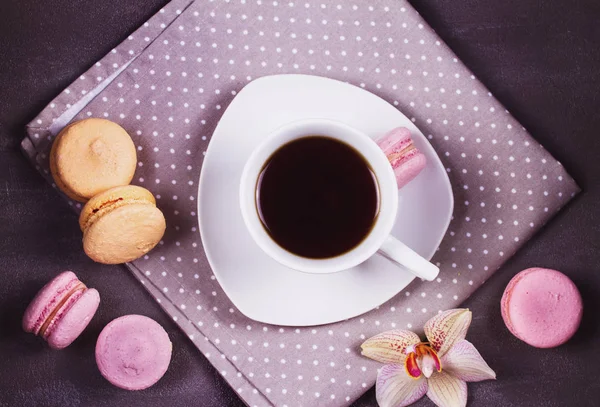 Coffee, orchids and cake macaron or macaroon on gray background from above. Flower, drink and coockie still life