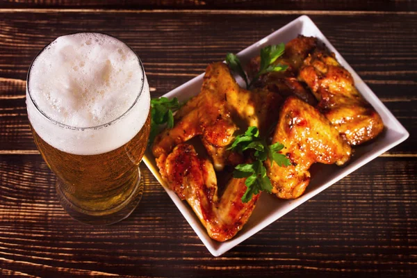 Un vaso de cerveza y alas de pollo de búfalo. Picaduras de cerveza —  Fotos de Stock