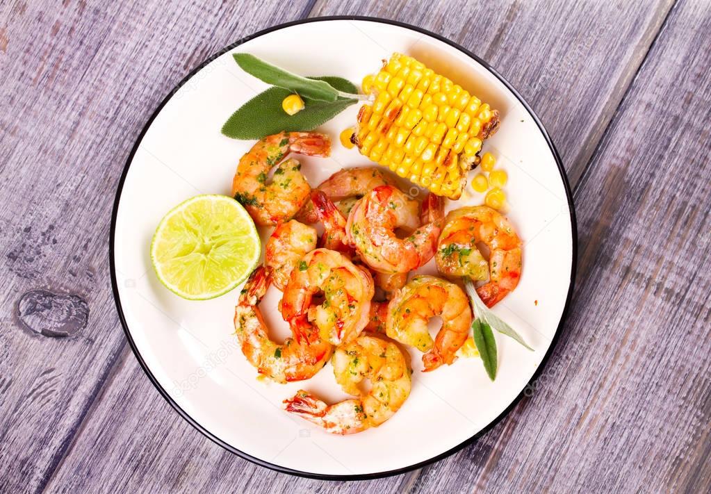 Grilled shrimps and corn garnished with lime and sage leaves