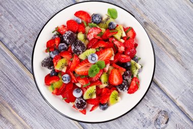 Çilek, böğürtlen, yaban mersini ve kivi salata, nane ile süslenmiş
