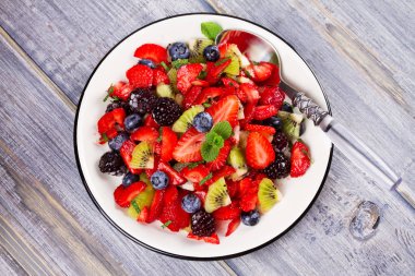 Çilek, böğürtlen, yaban mersini ve kivi salata, nane ile süslenmiş