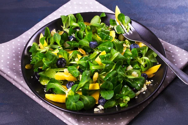 Lechuga de cordero, mango, arándanos y ensalada de queso en plato negro — Foto de Stock