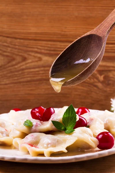 Varenyky, vareniki, pierogi, pyrohy ou boulettes, remplis de cerises, peuvent être servis avec du beurre et du miel. Varenyky avec remplissage de baies — Photo