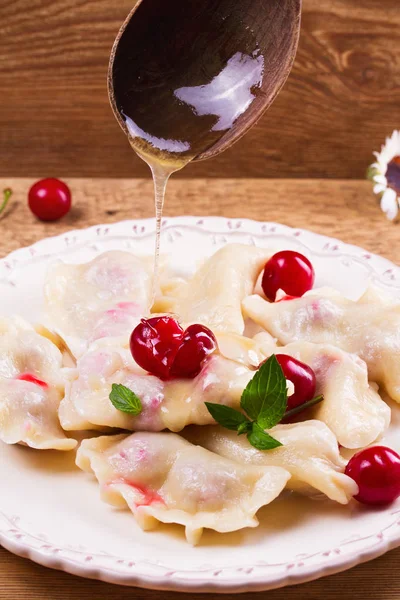 Varenyky, vareniki, pierogi, pyrohy or dumplings, filled with cherries, can be served with butter and honey. Varenyky with berries filling — Stock Photo, Image