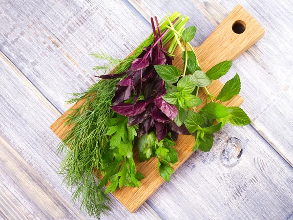 Kruiden op houten snijplank: Dille, peterselie, munt en basilicum. Culinaire kruiden voor het koken en eten bijgerechten — Stockfoto