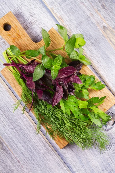 Kruiden op houten snijplank: Dille, peterselie, munt en basilicum. Culinaire kruiden voor het koken en eten bijgerechten — Stockfoto