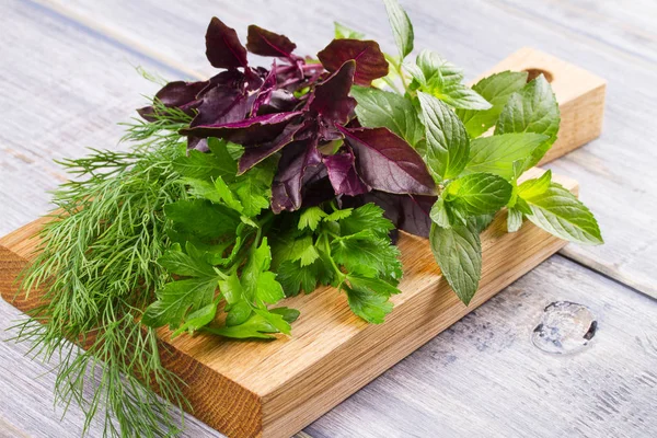 Kruiden op houten snijplank: Dille, peterselie, munt en basilicum. Culinaire kruiden voor het koken en eten bijgerechten — Stockfoto