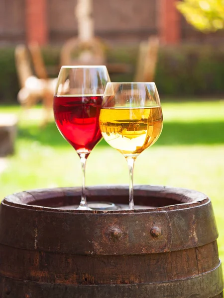 Окуляри червоного та білого вина з виноградом на старій винній бочці зовні — стокове фото