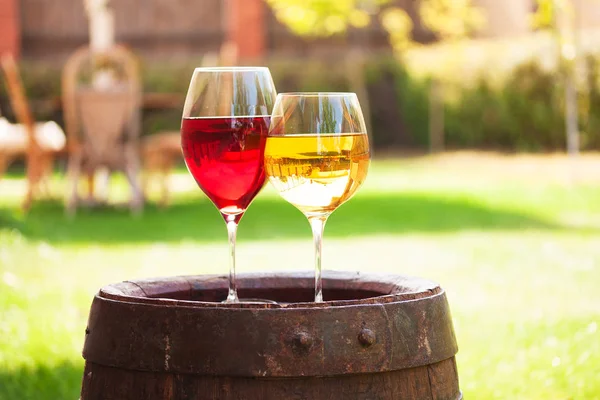 Bicchieri di vino rosso e bianco con uva su botte di vino vecchio fuori — Foto Stock