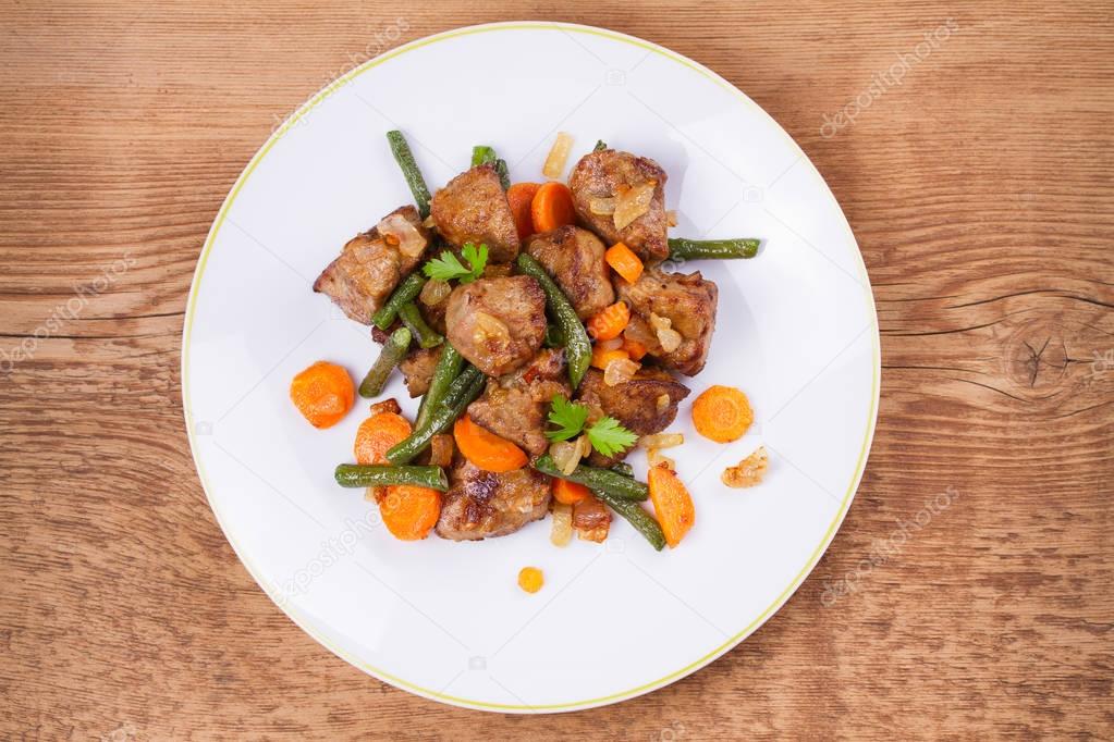 Sauteed liver with vegetables on white plate