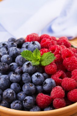 Yaban mersini ve ahududu kil kase. Taze çilek rustik arka plan üzerinde aldı