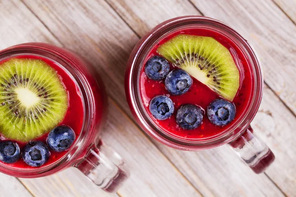 Berry kiwi smoothie in the jars, garnished with blueberries and kiwi — Stock Photo, Image