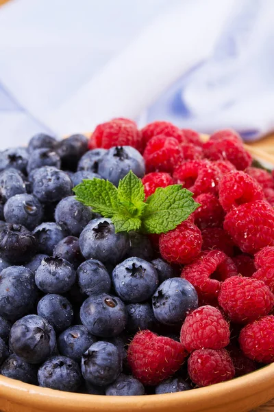 Yaban mersini ve ahududu kil kase. Taze çilek rustik arka plan üzerinde aldı