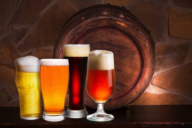 Bira çeşitli bardak kiler, pub veya restoran ayarlamak. Bira gözlük, eski bira varil ve tuğla duvar arka plan üzerinde