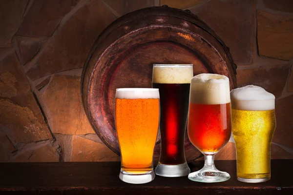 Bira çeşitli bardak kiler, pub veya restoran ayarlamak. Bira gözlük, eski bira varil ve tuğla duvar arka plan üzerinde — Stok fotoğraf