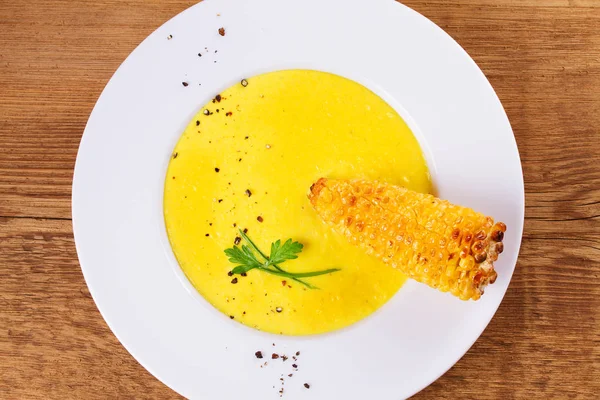 Cream corn soup in bowl on wooden background