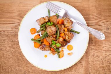 Sebze ile karaciğer sığır eti: havuç, soğan ve yeşil fasulye beyaz plaka üzerinde