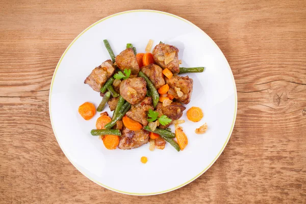 Sebze ile karaciğer sığır eti: havuç, soğan ve yeşil fasulye beyaz plaka üzerinde