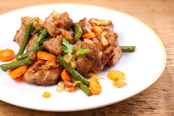 Sebze ile karaciğer sığır eti: havuç, soğan ve yeşil fasulye beyaz plaka üzerinde