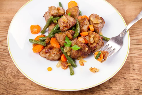 Sebze ile karaciğer sığır eti: havuç, soğan ve yeşil fasulye beyaz plaka üzerinde