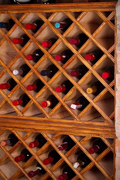 Bottles of wine on wooden shelves in wine cellar — Stock Photo, Image
