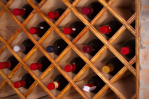 Bottles of wine on wooden shelves in wine cellar — Stock Photo, Image