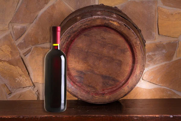 Bottle of red wine and old wine barrel in cellar — Stock Photo, Image