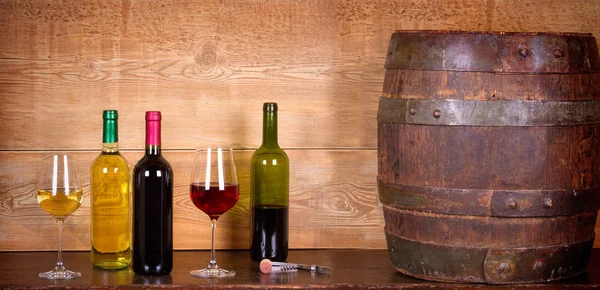 Still life with bottles and glasses of red and white wine with cheese, prosciutto and grape in wine cellar, old wine barrel — Stock Photo, Image