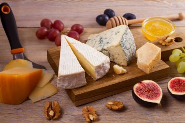 Peynir tabağı. Üzüm, bal, incir ve rustik ahşap masa fındık ile peynir türleri