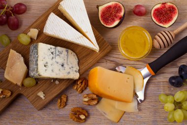 Peynir tabağı. Üzüm, bal, incir ve rustik ahşap masa fındık ile peynir türleri