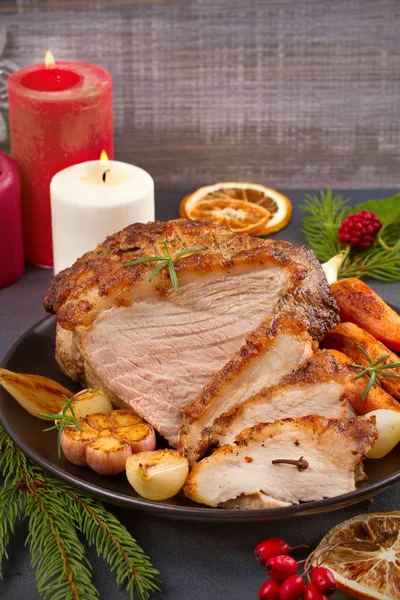 Gebratener Weihnachtsschinken auf Teller mit Gabel, Messer und festlicher Dekoration auf dunklem rustikalem Hintergrund — Stockfoto