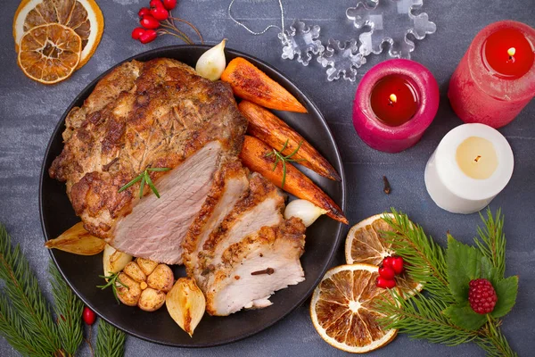 Gebratener Weihnachtsschinken auf Teller mit Gabel, Messer und festlicher Dekoration auf dunklem rustikalem Hintergrund — Stockfoto