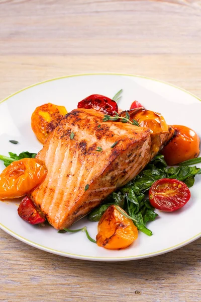 Salmon fillet with spinach and tomatoes on white plate — Stock Photo, Image