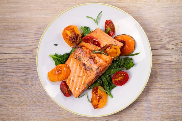 Salmon fillet with spinach and tomatoes on white plate — Stock Photo, Image