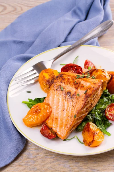 Salmon fillet with spinach and tomatoes on white plate — Stock Photo, Image