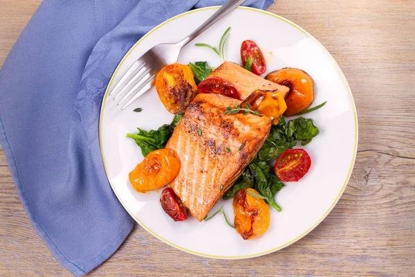 Salmon fillet with spinach and tomatoes on white plate — Stock Photo, Image