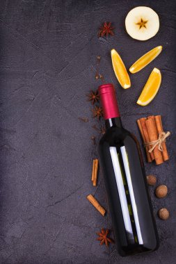 Bir şişe kırmızı şarap ve siyah arka plan üzerinde mulled şarap malzemeler. Baharat ve meyve sıcak alkol içki için