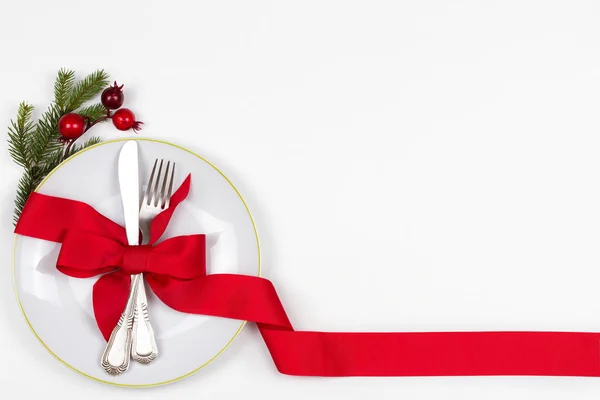 Noel sofra tabak, çatal bıçak takımı, Çamın dalları, şerit ve kırmızı meyveler ile yer. Kış tatili ve festival arka plan. Noel arifesi Akşam Yemeği, yılbaşı yiyecek Öğle Yemeği