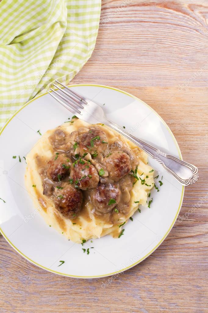 Meatballs with mushroom gravy and mashed potato on white plate