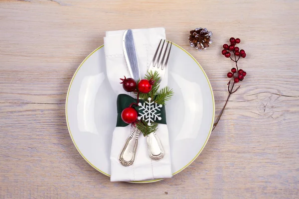 Conjunto de Natal com prato, talheres, ramos de pinho, canela e bagas vermelhas no lugar de madeira. Férias de inverno e fundo festivo. Jantar de véspera de Natal, almoço de comida de Ano Novo — Fotografia de Stock