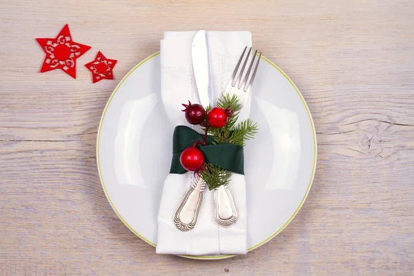 Weihnachts-Set mit Teller, Besteck, Tannenzweigen, Zimt und roten Beeren auf Holzplatz. Winterurlaub und festlicher Hintergrund. Heiligabend Abendessen, Neujahr Essen Mittagessen — Stockfoto